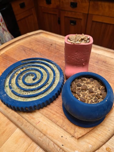 Three filled Freezbone toys, including a blue FreezSwirl and FreezBall, on a cutting board
